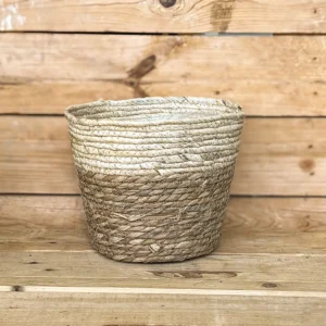 Macetero de anea natural con borde crema, ideal para aportar calidez y un toque rústico a la decoración de tu hogar combinado con plantas de interior. Su diseño trenzado y su acabado en fibras naturales lo convierten en un complemento perfecto para vestir tus plantas.