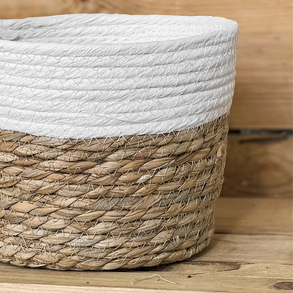 Macetero de anea natural con borde blanco, perfecto para aportar un toque cálido y natural a la decoración de tu hogar. Su diseño trenzado combina fibras naturales y un acabado claro que encaja fácilmente en cualquier ambiente con plantas de interior.
